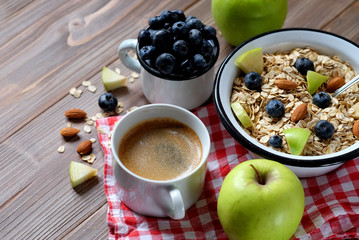A healthy breakfast is a great start to a new day. Oatmeal porridge, coffee, apple, berries and nuts on a wooden table. Top view.