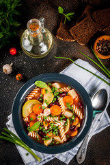 Italian vegetable soup Minestrone with fusilli pasta,  vegetarian food concept, dark rusty background, copy space