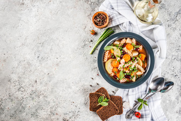 Italian vegetable soup Minestrone with fusilli pasta,  vegetarian food concept, grey stone background, copy space
