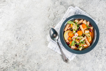 Italian vegetable soup Minestrone with fusilli pasta,  vegetarian food concept, grey stone background, copy space