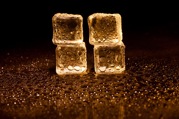 Golden ice cubes on black background.