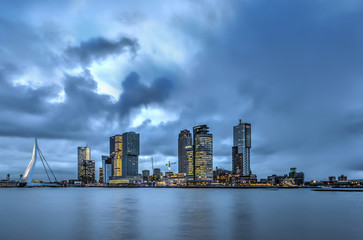 Naklejka premium A dramatic sky at dwan over the Erasmus bridge and the Kop van Zuid modern highrise in Rotterdam, The Netherlands