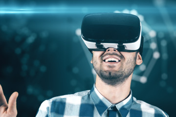 A young man with a beard in glasses of virtual reality on a technological background