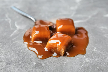 Delicious candies with caramel sauce on table