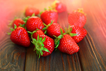 Morning strawberry crop on a wooden background. Handful of berries on a morning cuisine.