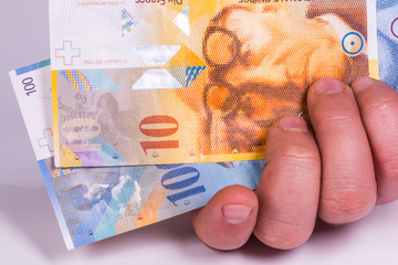 A man holds in his hand a Swiss banknote close-up