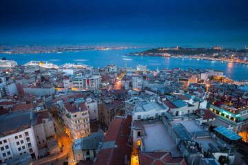 Naklejka premium Long exposure panoramic cityscape of Istanbul at a warm calm evening from Galata to Golden Horn gulf. Wonderful romantic old town at Sea of Marmara. Bright light of street lighting. Istanbul. Turkey.