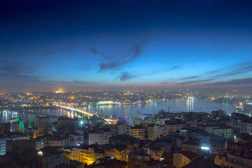 Long exposure panoramic cityscape of Istanbul at a warm calm evening from Galata to Golden Horn gulf. Wonderful romantic old town at Sea of Marmara. Bright light of street lighting. Istanbul. Turkey.