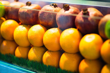 Oranges and pomegranates behind the glass in showcase. Fresh fruits Oranges and pomegranates behind the glass in showcase. Fresh fruits at food store show window