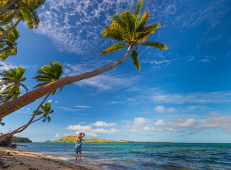Woman gazing at blue ocean under palm trees at beach