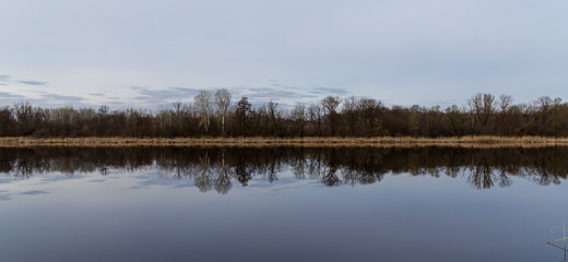 The sky and the forest are reflected in the water.