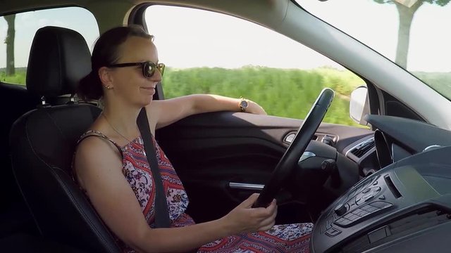 car driving - a young brunette  woman with sunglasses drives a car  - view at the driver inside
