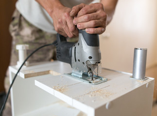 A man cuts out a wooden board with a jigsaw