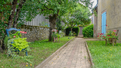 Feneyrols, Midi Pyrenees, France - July 23, 2017: Small garden with a set of chairs decorated with flowers and a central corridor