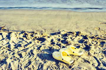 Daylight view to a pair of yellow flip-flops on sand