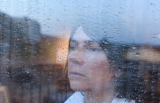 Woman Looking Out The Window On A Rainy Day