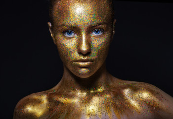 beautiful girl face, painted with gold paint with glitter. particles of a volatile powder. metallic.