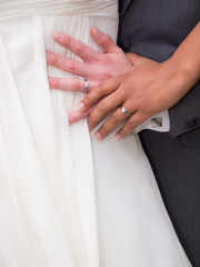 Obraz premium Bride and Groom Hands and rings on wedding dress close up