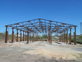 Metal frame of an industrial building. Objects of unfinished construction. Iron beams and concrete floors of the building.