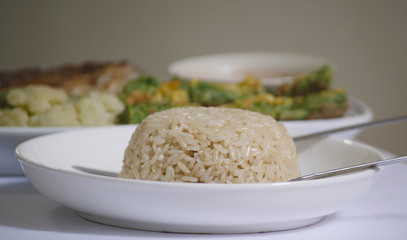 Brown Rice : on white Dish and blured steamed vegetale background