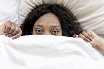 Afraid black woman under bed blanket