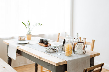 Canteen. wooden dining table with crockery and Cutlery. Light natural interior. Home comfort.
