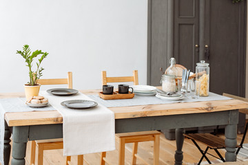 Canteen. wooden dining table with crockery and Cutlery. Light natural interior. Home comfort.