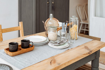 Canteen. wooden dining table with crockery and Cutlery. Light natural interior. Home comfort.