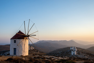 A windmill at the top of the Chora of Amorgos with a series of deserted windmills at the background - obrazy, fototapety, plakaty