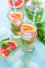 Refreshment grapefruit cocktail with mint on mint color background. Healthy citrus summer drink.