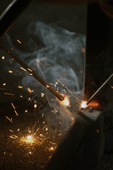 Worker is welding sparks table steel in factory.