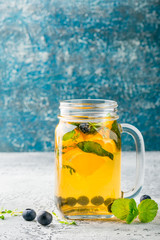 Orange Blueberry Detox Water or lemonade with mint in glass jar on ligth table