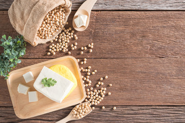 Tofu and yellow tofu with soybean on wood background.