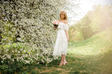 Girl standing between branches of spring white tree