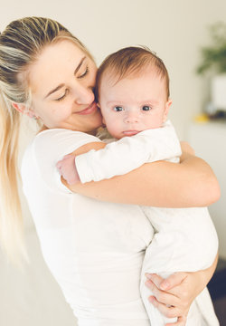 Toned portrait of adorable 3 months old baby with smiling mother
