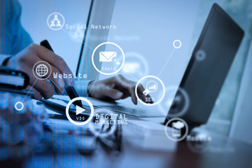 designer hand working with stylus and digital tablet and laptop on wooden desk in office