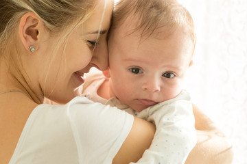 Closeup portrait of happy smiling mother and adorable 3 months old baby in sun rays