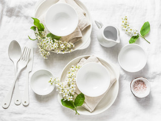 Served empty table with white crockery, flowers, napkins on white background, top view. Cozy home serving food table concept