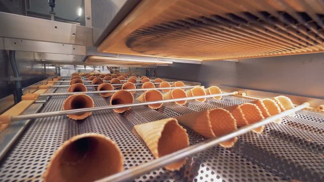 Horizontal rows of empty wafer cones are moving along metal ducts