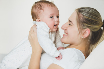 Toned portrait of lying young woman holding her 3 months old baby