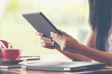 Woman hand holding tablet and using tablet in coffee shop.