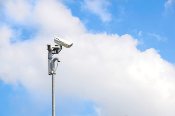 Security camera install corner outside of building with blue sky background.