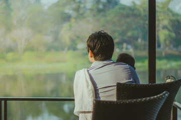 Dad and son  waiting for mom on the waterfront balcony in the mo