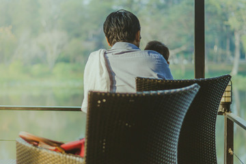 Dad and son  waiting for mom on the waterfront balcony in the mo