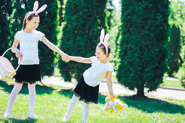 two little girls play in a meadow and hunt for Easter eggs