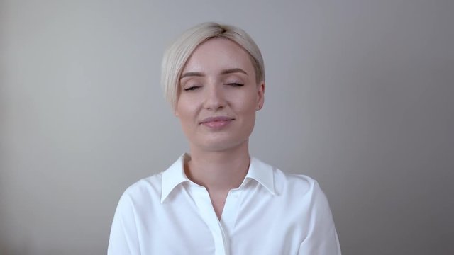 Closeup of young blonde woman uses a makeup fixation spray onto her face.