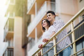 Lovely happy couple relax and have fun at balcony in their new home apartment