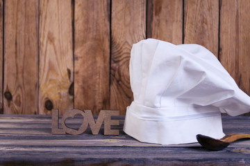 Fototapeta na wymiar Chef's cap on an old wooden background, I love to cook
