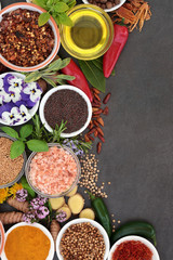 Herb and spice abstract background border with fresh and dried herbs, spices and edible flowers on slate background. Top view.