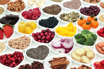 Nutrition for a healthy heart with fresh vegetables, fruit, spices, pulses, nuts, seeds, fish and medicinal herbs. Super food concept, high in omega 3 fatty acids, fibre, vitamins and antioxidants.